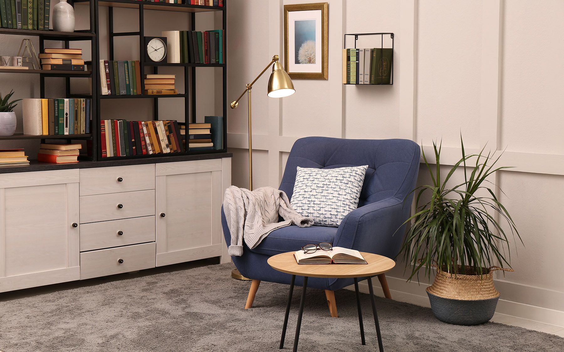 Čítací kútik v obývačke s modrým kreslom, stolíkom a doplnkami.