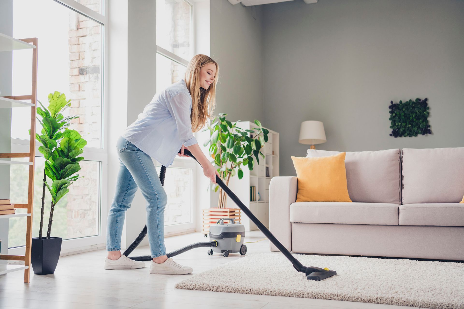Žena vysáva koberec v obývačke.