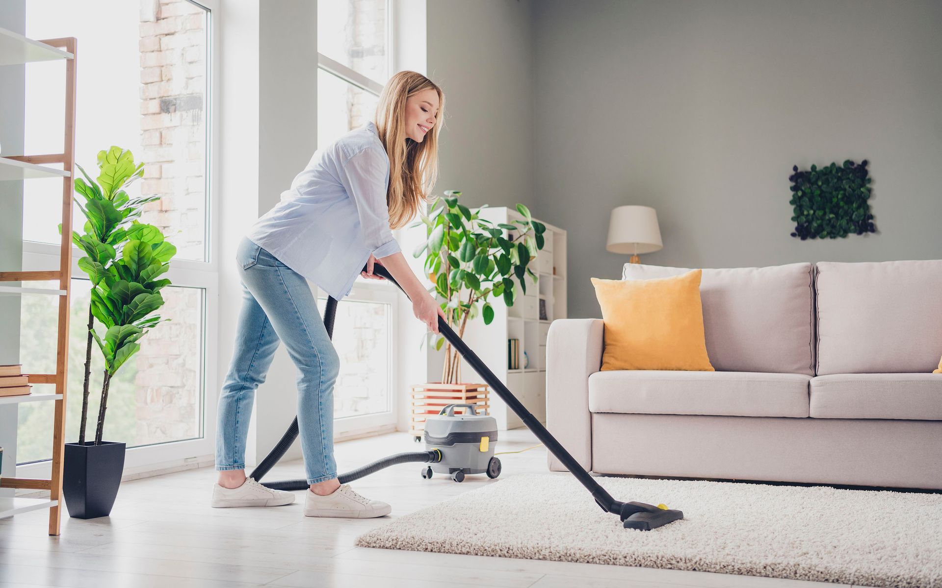 Žena vysává koberec v obýváku.