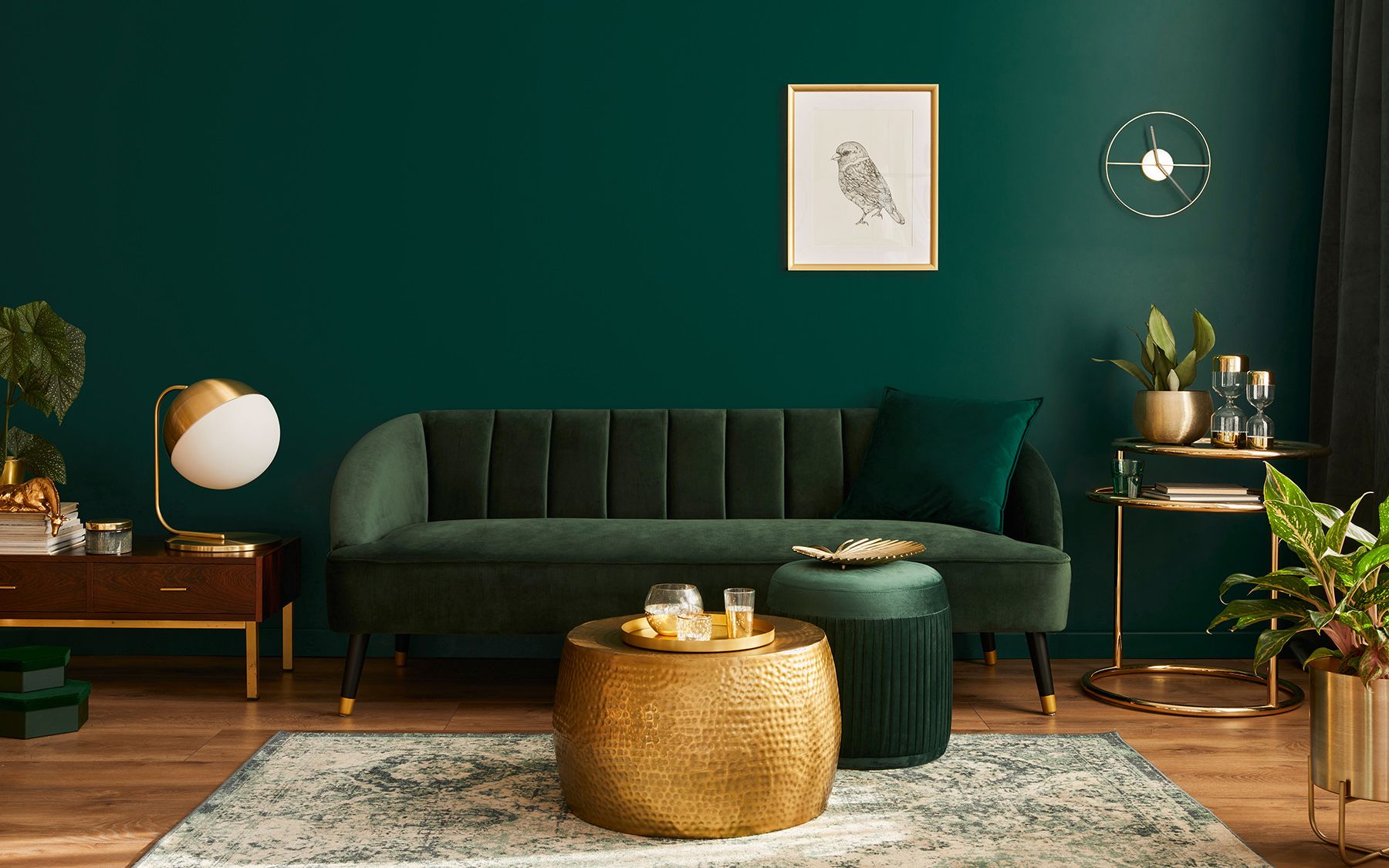 Obývák v zelené a zlaté barvě s kovovými doplňky a kusovým kobercem.