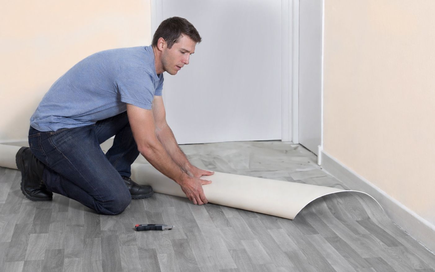 Muž pokládá PVC podlahu na špatný podklad.