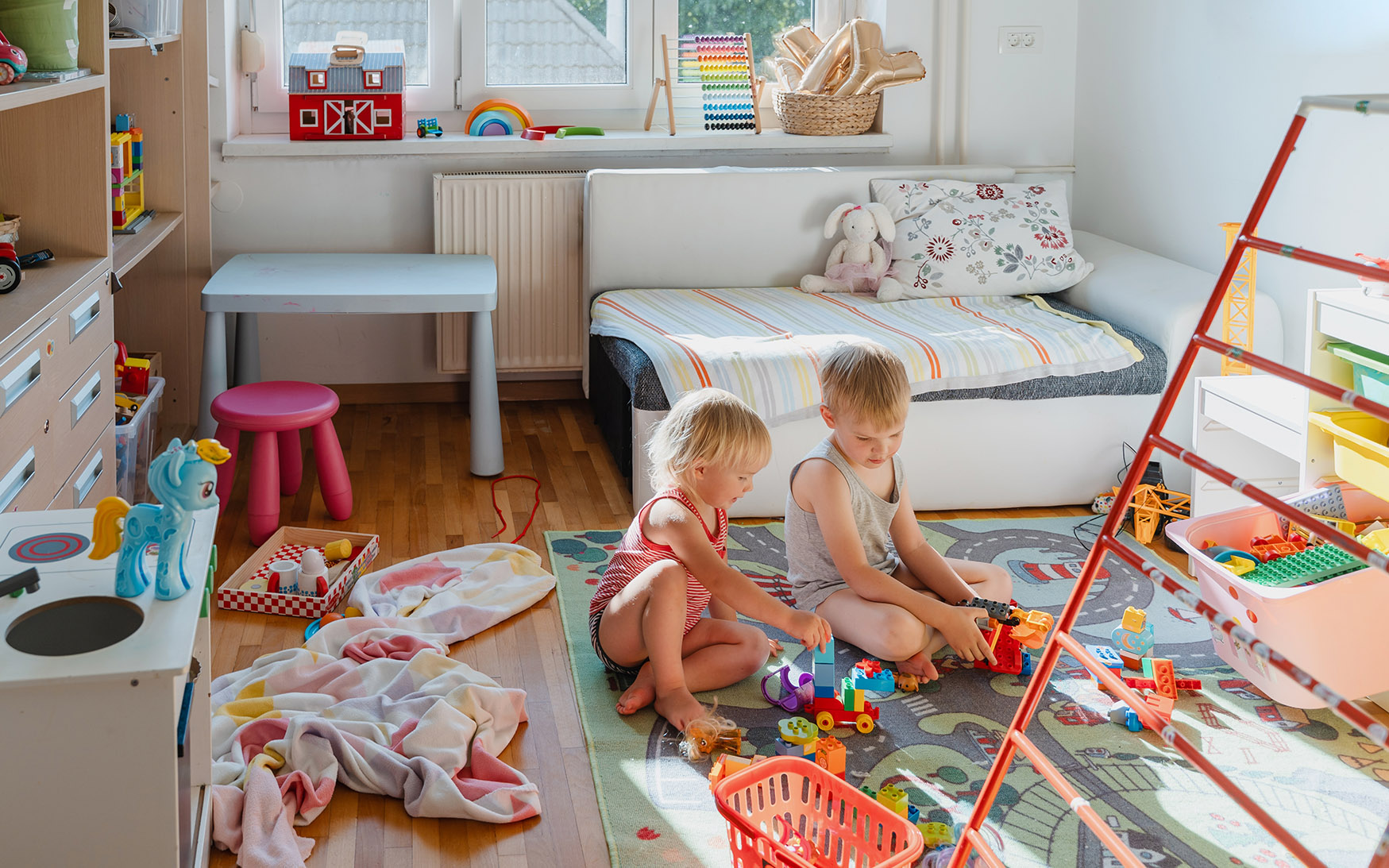 děti si hrají v pokojíčku na koberci se silnicemi a cestami