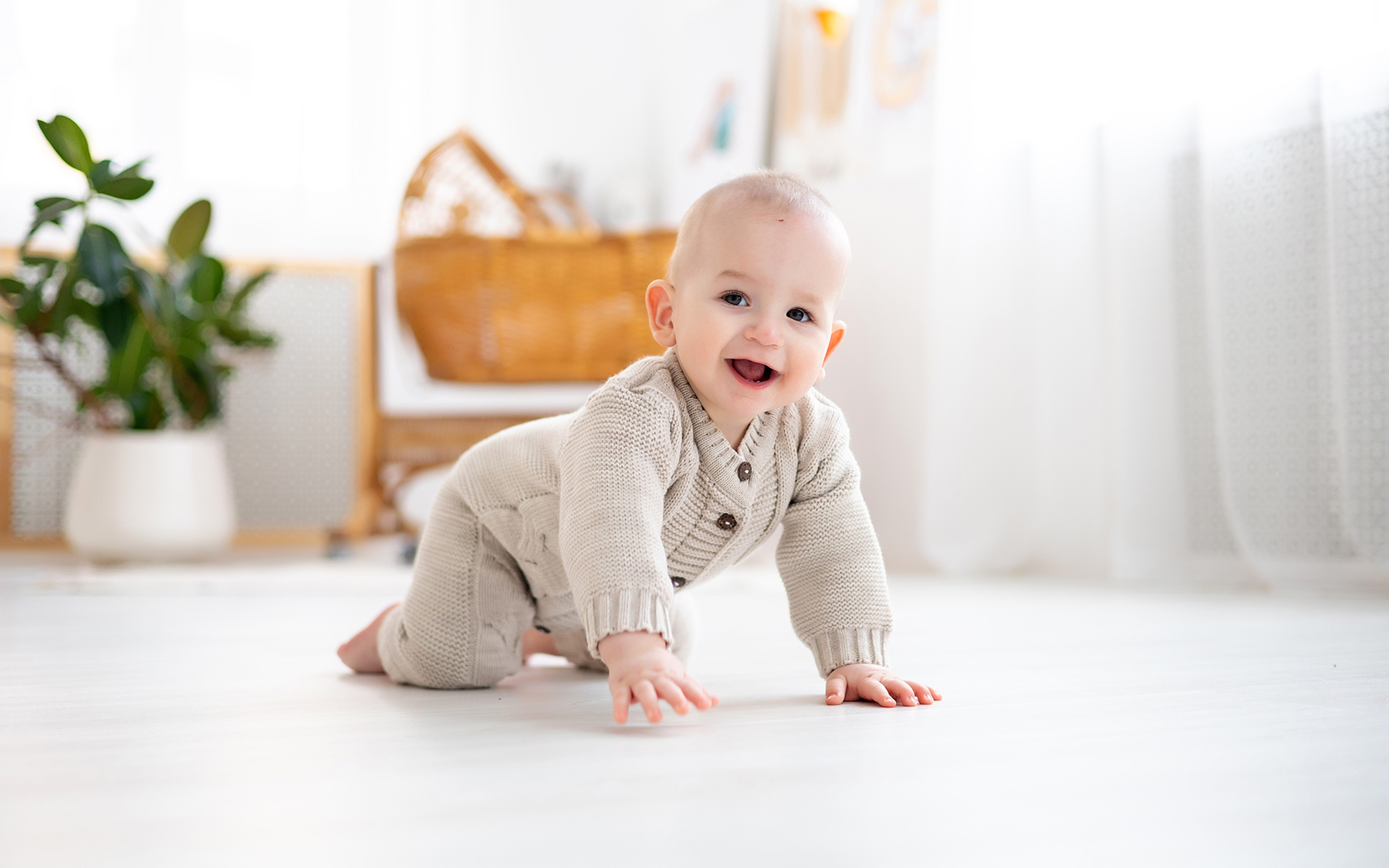 Batoľa sa plazí po vinylovej podlahe a smeje sa.