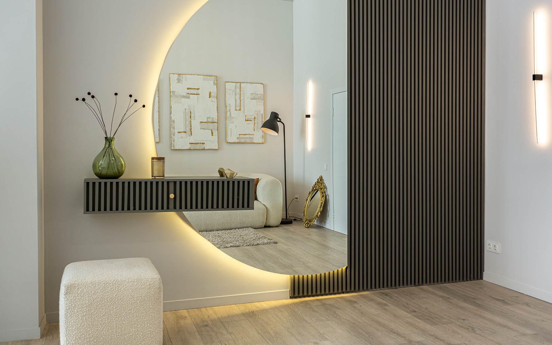 Moderně zařízená chodba s půlkruhovým podsvíceným zrcadlem a akustickými panely.