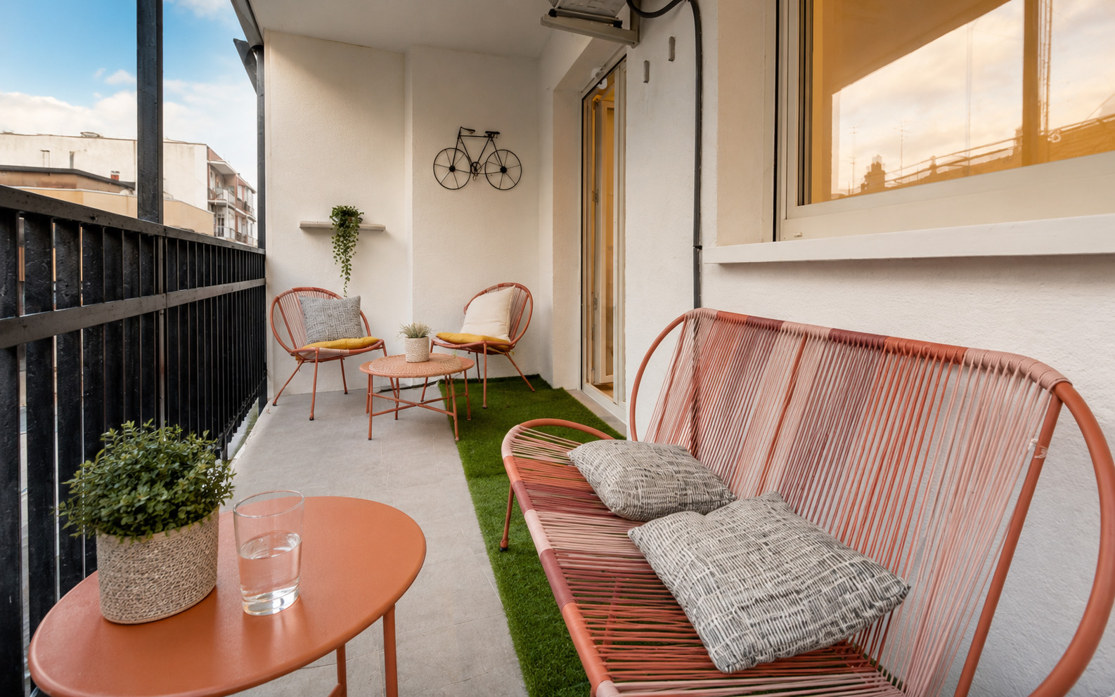 Malý balkon s posezením, dlažbou a umělou trávou.