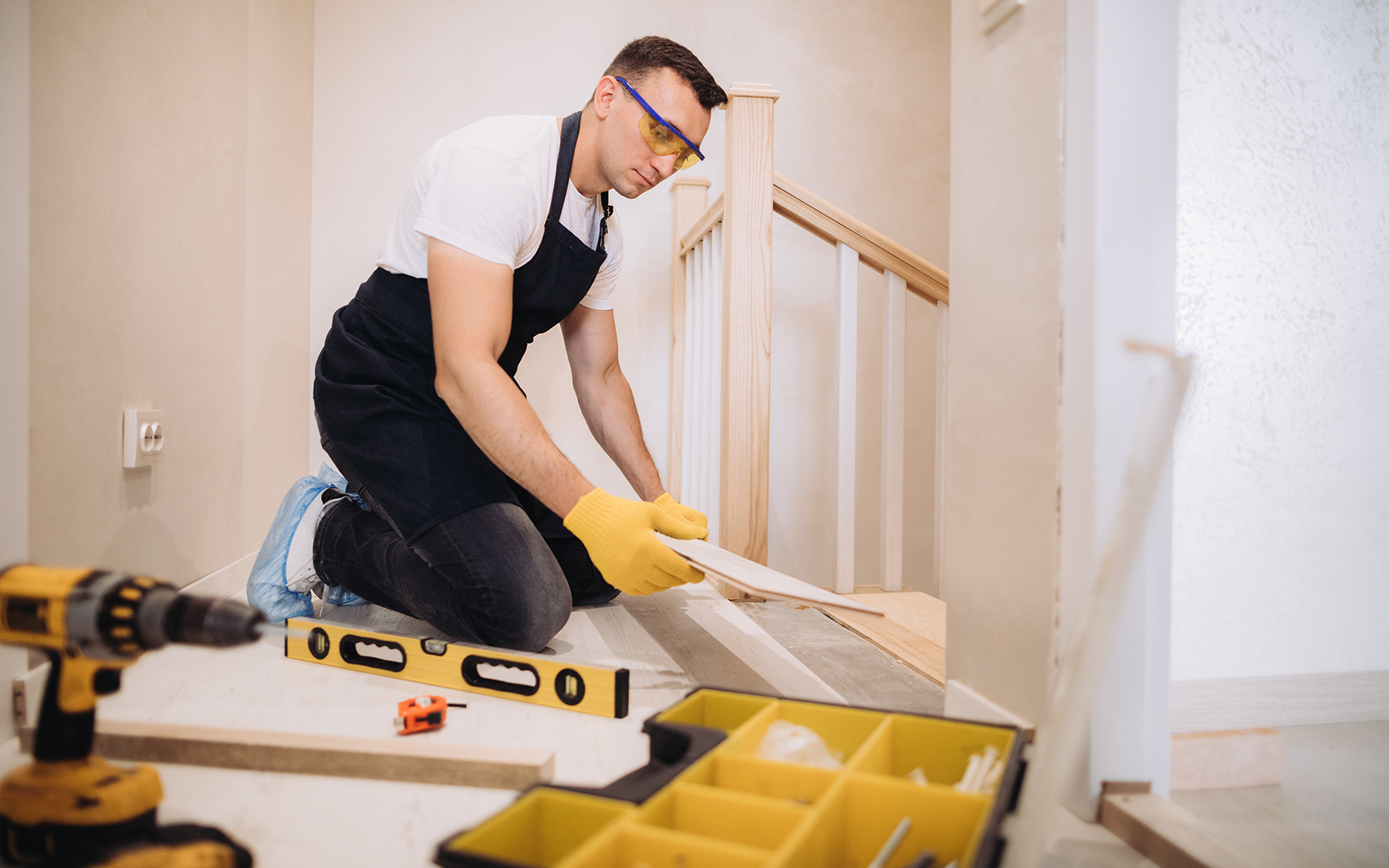 Muž pokladá lepený vinyl na schody.